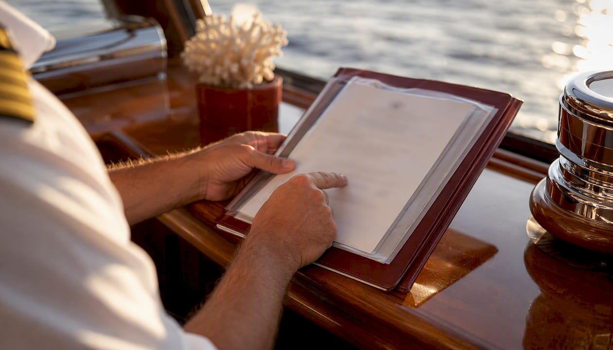 Hands holding yacht's International Tonnage Certificate folder