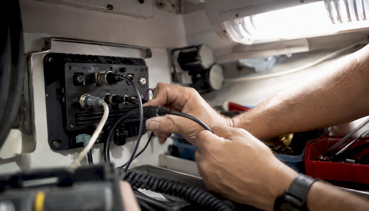 Hands connecting programming cable to AIS transceiver