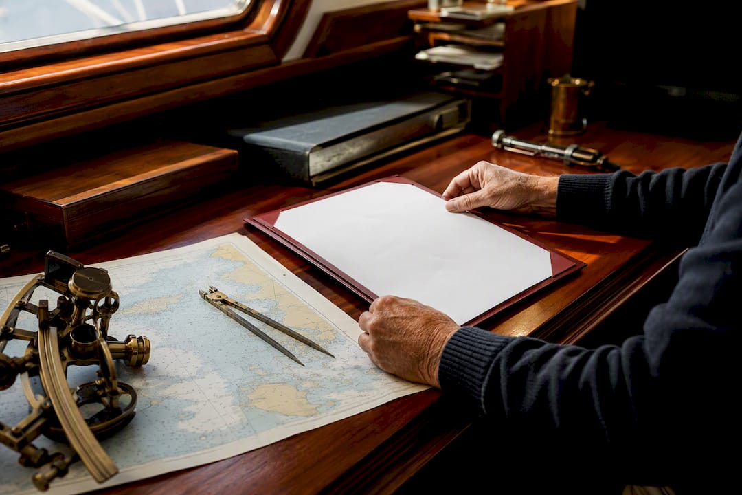 Hands handling yacht certificate and nautical tools