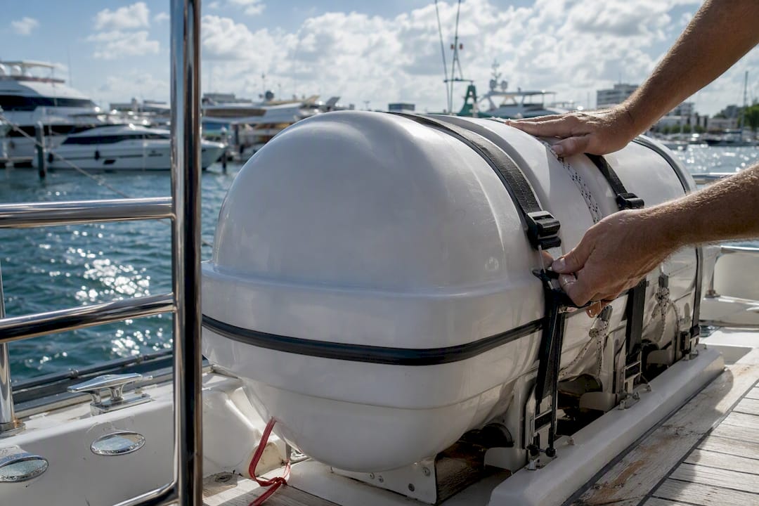 Hands securing yacht life raft container on deck