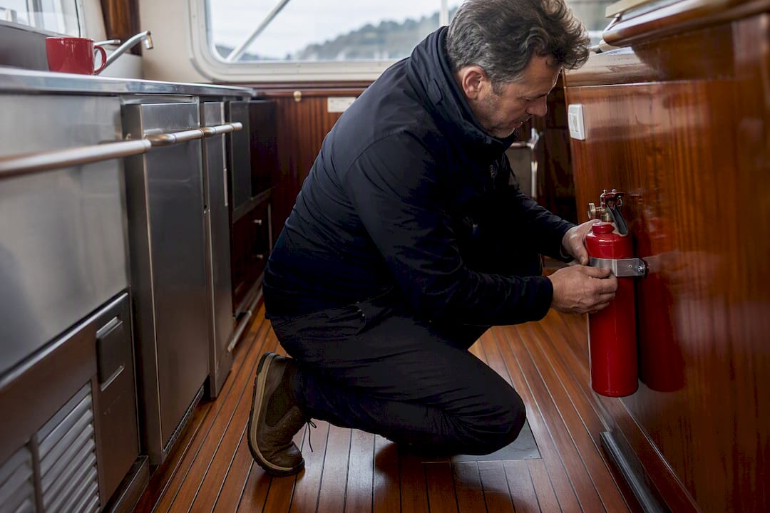 Hands securing fire extinguisher inside yacht cabin