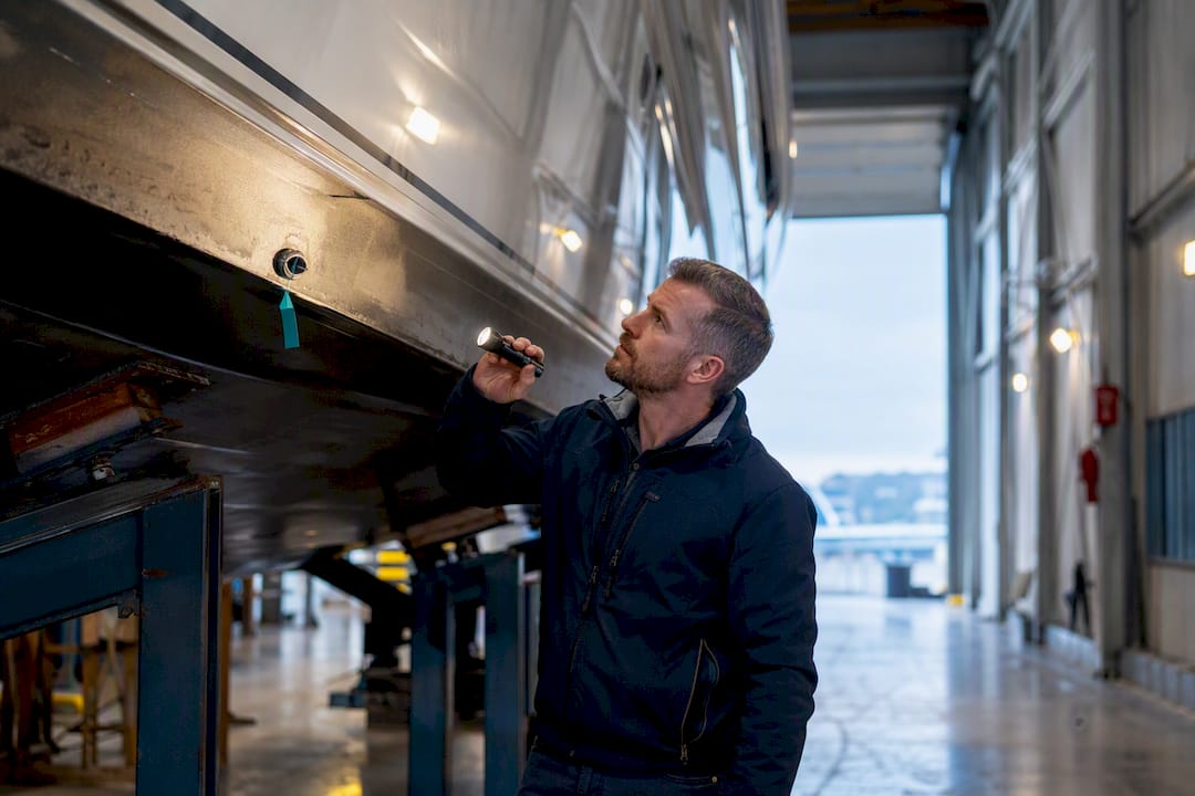 Surveyor inspecting yacht hull in shipyard