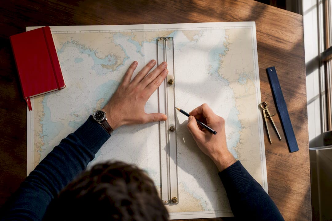 Hands plotting a course on nautical chart